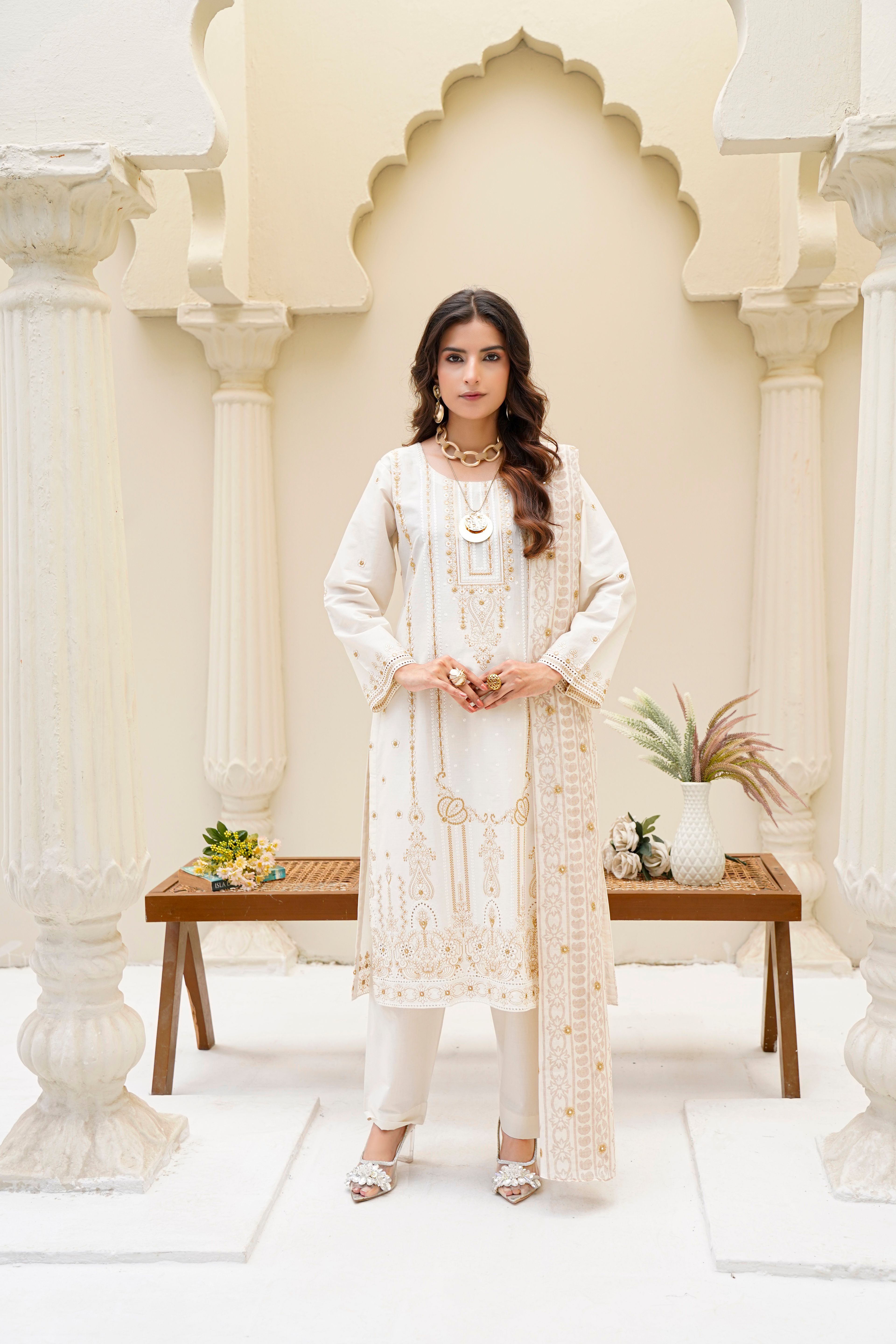 Ivory embroidered outfit in a sunlit courtyard